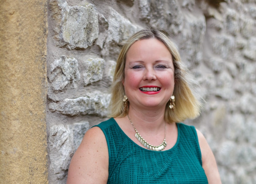 Debbie Nuttall, Client Support Specialist at Toggle Switch Consulting, smiling in front of a stone wall, representing supportive business change and people-focused client success